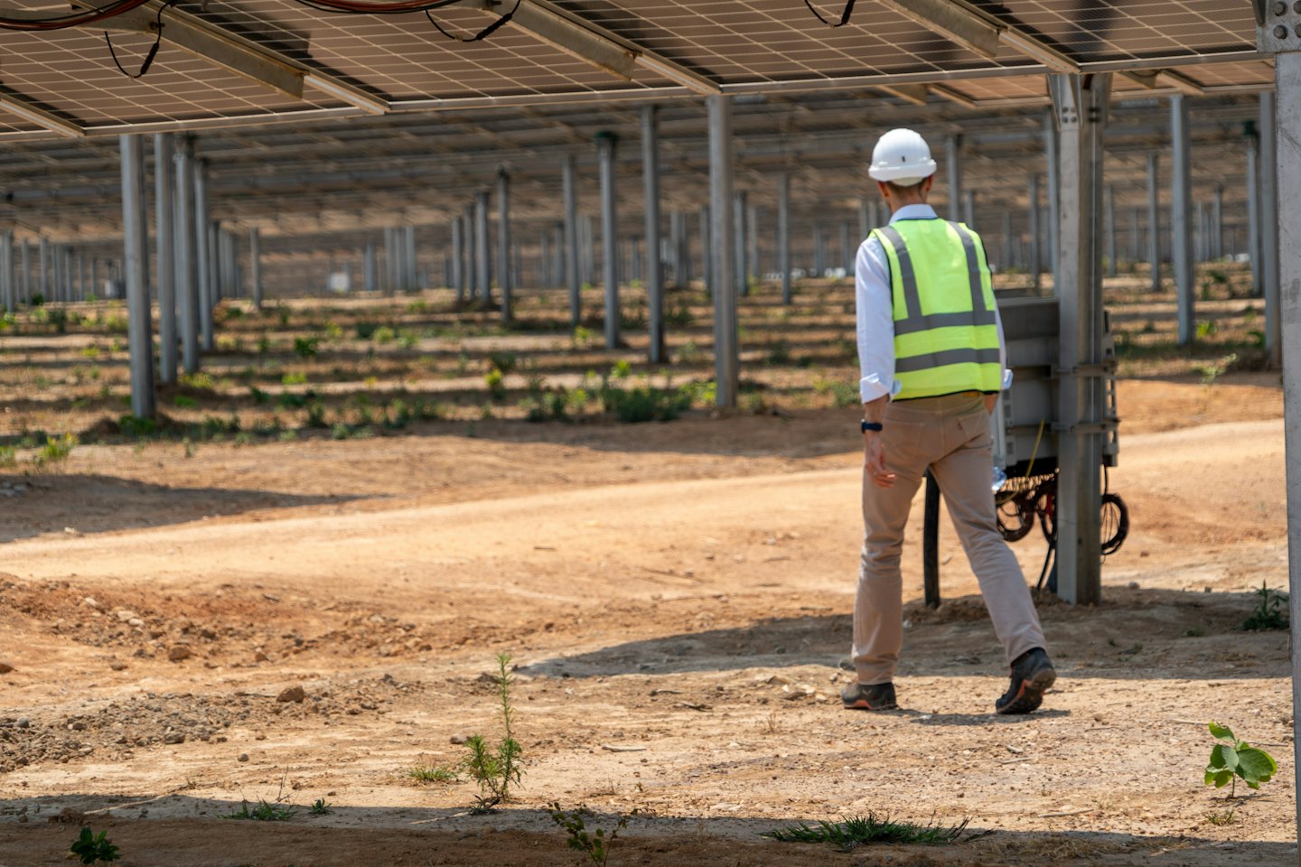 Technician in hard hat inspects solar farm.